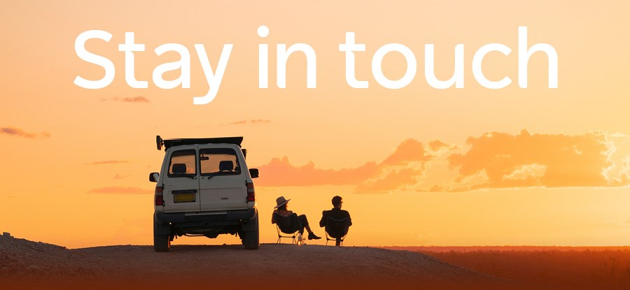 A 4WD car on a dessert sunset with 2 adults in camp chairs beside it.