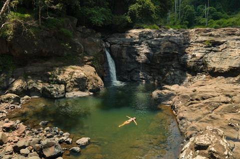Woman floating near a waterfall
